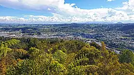 Looking westward towards central Whangārei from the Mount Parihaka lookout, with Te Matau A Pohe bridge and the suburb of Port Whangārei to the far left, the Discovery Settlers Hotel in the suburb of Regent to the far right, as well as Maungatapere and Te Tangihua in the background.