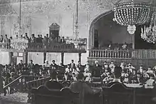 Large hall with two balconies, filled with men