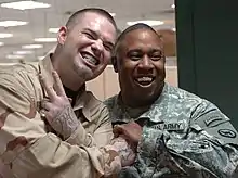 "Paul Wall, wearing grills, poses for a picture with a smiling soldier, also clad in grills."