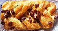 A Danish pastry topped with pecans and maple syrup