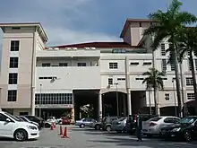 A hospital building with cars parked nearby and trees to the right.