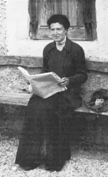 Photograph of a woman sitting and reading a newspaper