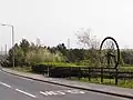 This memorial pit wheel was put in place in 1990. The tree-lined area to the rear covers the site of the actual colliery. The road is the former High Street. Photograph taken in May 2006