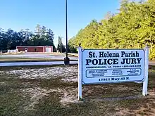 Buildings in background. Sign in foreground reads St. Helena Parish Police Jury, Office of Homeland Security, Building Permits, E-911 Administrator Office with individual phone numbers and collective address.