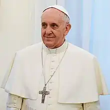 Pope Francis in white, smiling and looking to the left