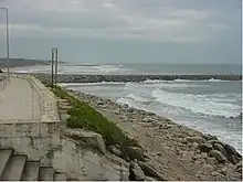 Stone Seawall with cemented walkway, mud revetment stabilized with grass, and gravel riprap armament at the base.