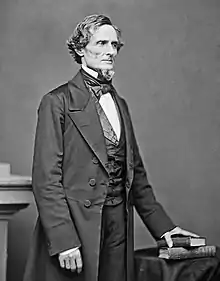 Middle-aged man in a goatee posed standing in a suit, vest and bowtie