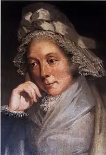 Quarter-length portrait, showing a woman in a brown and gray lace bonnet with a bow and leaning on her right hand.