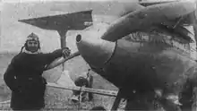 Old photo of pilot standing next to R-1 racer airplane