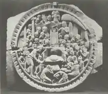 Stone relief with throne at the center and numerous figures surrounding the throne, including a mother and her child