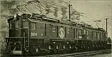 Two sequentially-numbered American boxcab locomotives coupled together at the head of a train. Each has its own diamond-shaped pantograph raised.