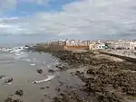 A seaside view of a large city enclosed by an orange barricade.