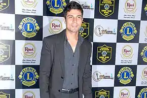 Hooda in a grey suit posing for the camera.