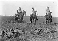 Capt. Monroe Fox and two other Rangers on horseback with their lariats around the bodies of dead Mexican bandits, after the Norias Ranch Raid August 8, 1915