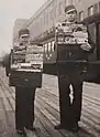  Two boys standing next to each other holding display cases of magazines on a railway platform. Rautavaara is the taller boy on the right.