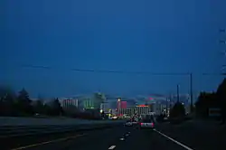 Dusk view of a freeway descending into a neon lit cityscape