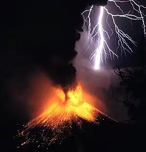 A photograph depicting a white bolt of lightning with a purple aura striking a volcano as it erupts yellow lava with a red aura and black smoke.