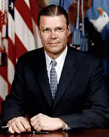 man in business suit, American flag in background