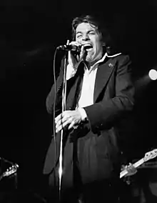 Palmer singing into a microphone onstage