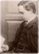 A small head-portrait of a young, pale man with dark hair.