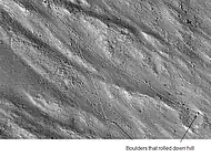 Enlargement of cliff in the Kasei Valles system in previous image showing boulders and their tracks, as seen by HiRISE. The boulders are around 2 m across.