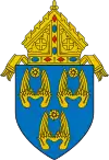 The arms of the Archdiocese of Los Angeles: The arms feature three pairs of wings, denoting three angels, and referencing the namesake of the see, Los Angeles, California, which translates to "the angels."