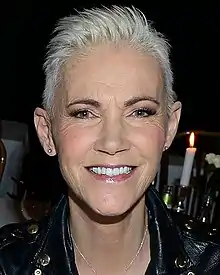 Fredriksson smiling into a camera. There is a flame from a candle flickering above her left shoulder.