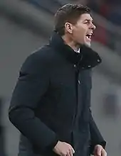 Gerrard shouting while wearing a black coat