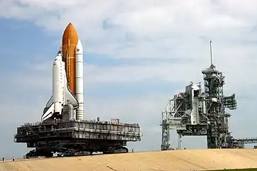 A crawler-transporter carrying  Discovery (STS-114) travels the ramp to Launch Pad 39B. The vehicle's back end can be raised, keeping the Shuttle and the MLP level.