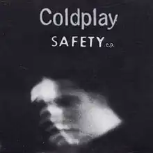 Blurred black and white photograph of Chris Martin in front of a door marked SAFETY.