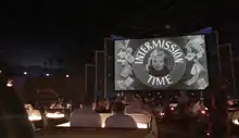 Patrons inside the car themed booths watching the screen.