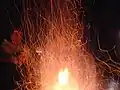 A campfire that seems to produce sparks, due to a long exposure when photographed.