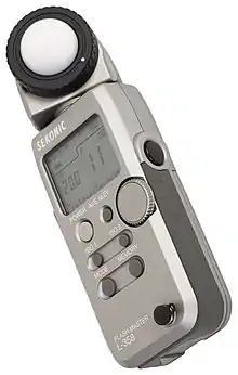 A handheld digital light meter showing an exposure of .mw-parser-output .frac{white-space:nowrap}.mw-parser-output .frac .num,.mw-parser-output .frac .den{font-size:80%;line-height:0;vertical-align:super}.mw-parser-output .frac .den{vertical-align:sub}.mw-parser-output .sr-only{border:0;clip:rect(0,0,0,0);clip-path:polygon(0px 0px,0px 0px,0px 0px);height:1px;margin:-1px;overflow:hidden;padding:0;position:absolute;width:1px}1⁄200th at an aperture of .mw-parser-output span.fnumber,.mw-parser-output .fnumber-fallback{display:inline-block;white-space:nowrap;width:max-content}.mw-parser-output span.fnumber::first-letter,.mw-parser-output .fnumber-fallback .first-letter{font-style:italic;font-family:Trebuchet MS,Candara,Georgia,Calibri,Corbel,serif}f/11, at ISO 100. The light sensor is on top, under the white diffusing hemisphere