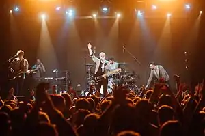 Everything Everything stand on an orange-lit stage in Kiev, Ukraine, mid-performance.