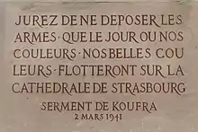 An inscription in stone, in French. It reads: "Jurez de ne déposer les armes que le jour où nos couleurs, nos belles couleurs flotteront sur la cathédrale de Strasbourg. 2 Mars 1941"