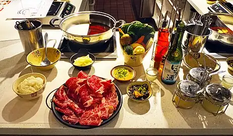 Sliced meat with sauces and two types of broth