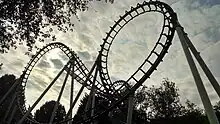 A shadowy view of the roller coaster's three inversions. The first inversion of the cobra roll is partially blocked by the vertical loop in the foreground.