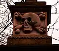 The skull and crossbones gatepost is from the nearby Church of St. Cuthbert with the Mausoleum.