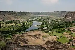 A canyon with land covered in a mix of grass and sand