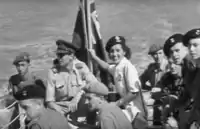 A Somerset Light Infantry Regiment member hoists the Civil Ensign