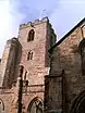 A stone church building with a tower. On the top of the tower, a Saltire flag flies on a pole.