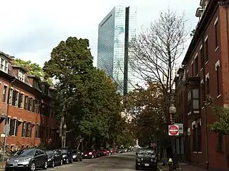 Old, tree-lined street with a modern building in the background