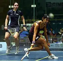 A teammate in a dark blue uniform jumps up while David passes the ball to her.