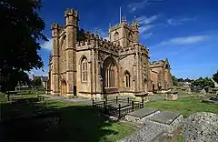 Decorated yellow stone building with square tower.