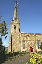 A Gothic-style steeple with part of the body of the church to the right