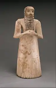 Standing male worshiper, one of the twelve statues in the Tell Asmar Hoard; 2900–2600 BC; gypsum alabaster, shell, black limestone and bitumen; 29.5 x 12.9 x 10 cm; Metropolitan Museum of Art