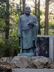 A statue of Ennin, an important disciple of Saicho with blue sky in the background, facing right