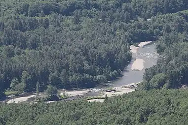 An aerial photograph of a sandy river flowing through a forest