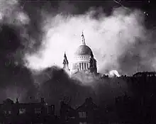 Black and White photograph of the dome of St Paul's, starkly lit, appearing through billowing clouds of smoke