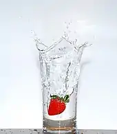 a glass of transparent water sitting on a wooden table